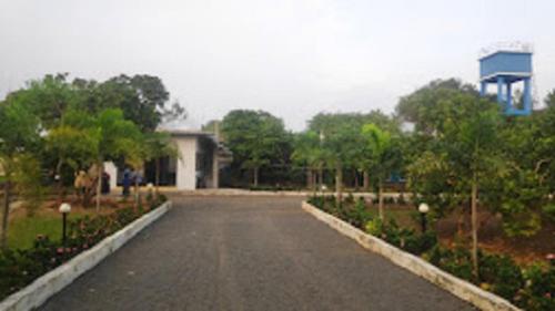 an empty road in a park with trees and a building at Paradise Forest Resort in Puducherry