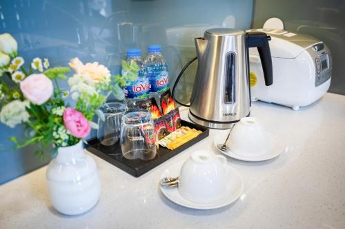 a counter with a coffee pot and cups and flowers at Five Star Westlake 1st-4th Floors Hotel & Serviced Apartment in Hanoi