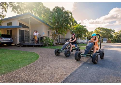 two women riding on four wheelers in front of a house at Discovery Parks - Coolwaters, Yeppoon in Kinka