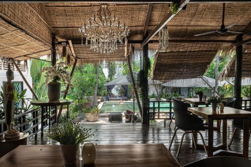 a restaurant with tables and chairs and a chandelier at La Bastide de Caro in Siem Reap