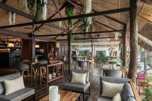 a restaurant with wooden ceilings and tables and chairs at La Bastide de Caro in Siem Reap