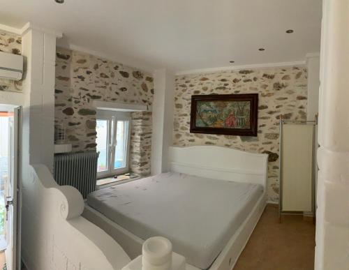 a white bed in a room with stone walls at Sea&Stone Apartment in Skala Sotiros