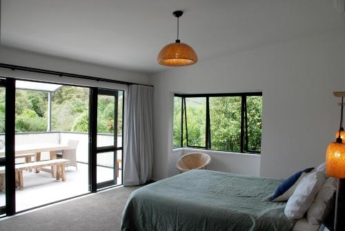 a bedroom with a bed and a table and windows at Lake View Okareka - Lake Okareka Holiday Home in Lake Tarawera