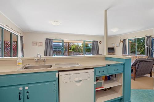 a kitchen with blue cabinets and a sink at Room for The Family - Bowentown Bach in Waihi Beach