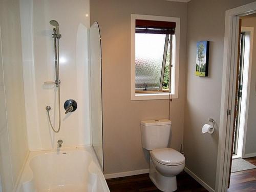a bathroom with a tub and a toilet and a window at 45 Below - National Park Holiday Home in National Park
