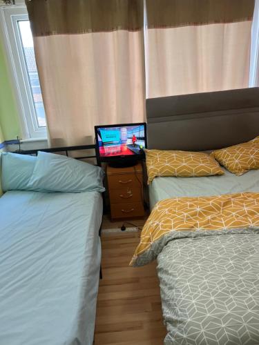 um quarto com 2 camas individuais e uma televisão em Luxury suite em Summerseat