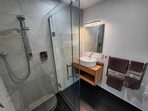 a bathroom with a sink and a glass shower at The Strand in New Plymouth