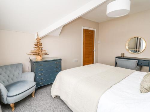 Un dormitorio con una cama, una silla y un espejo. en Welsh Valley House, en Brynamman