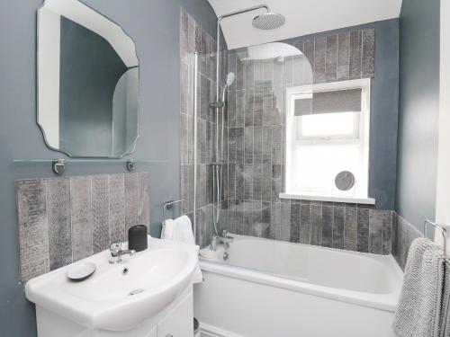 Un baño con lavabo, bañera y espejo. en Welsh Valley House, en Brynamman