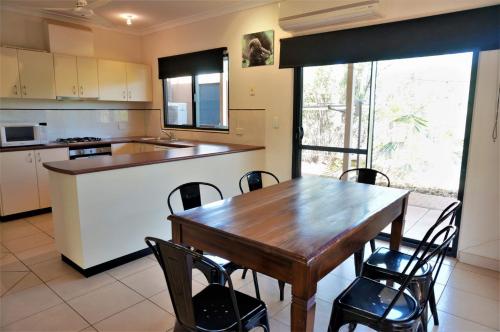 a kitchen with a wooden table and chairs in it at Ningaloo Breeze Villa 3 in Exmouth