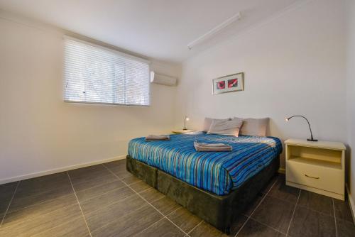 a bedroom with a bed with a blue comforter and a window at Getaway Villas Unit 3811 in Exmouth