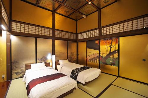 dwa łóżka w pokoju z obrazami na ścianach w obiekcie Hidatakayama Ukiyoe INN Garon - Vacation STAY 12320v w mieście Takayama