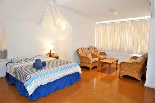 a bedroom with a bed and two chairs and a window at Osprey Holiday Village Unit 123 in Exmouth