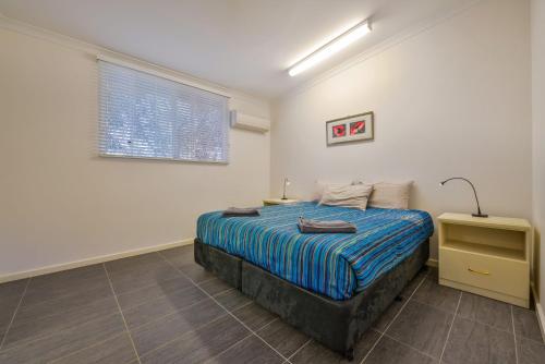 a bedroom with a bed and a lamp and a window at Getaway Villas Unit 384 in Exmouth