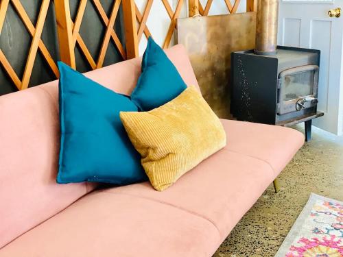 a pink couch with two blue pillows on it at Byron Bay Hinterland Eco-Retreat Ivory Yurt in Eureka