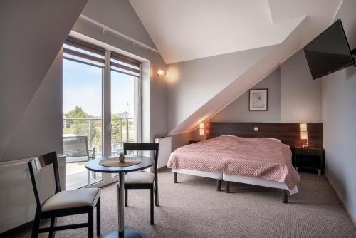 a bedroom with a bed and a table and a window at Villa Luka in Łeba