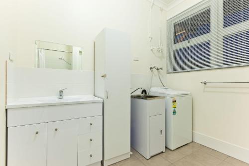 a white bathroom with a sink and a refrigerator at Exmouth Villas Unit 33 in Exmouth