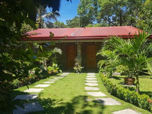 a house with a red roof and a grass yard at Mountain View Cottages in Mambajao