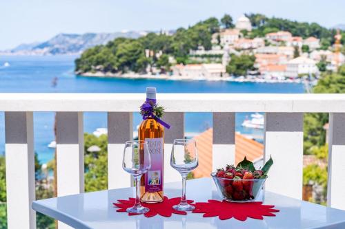 einen Tisch mit einer Flasche Wein und einer Schale Obst in der Unterkunft Apartments Mara & Petrunjela in Cavtat