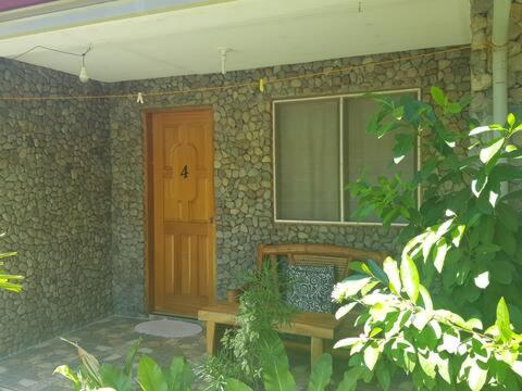 a building with a door and a bench in front of it at Mountain View Cottages in Mambajao