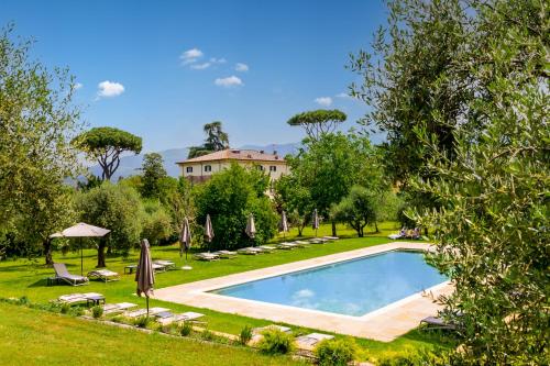 Hotel Villa San Michele في لوكّا: حمام سباحة في حديقة مع منزل في الخلفية