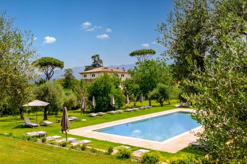 a swimming pool in a garden with a house in the background at Hotel Villa San Michele in Lucca