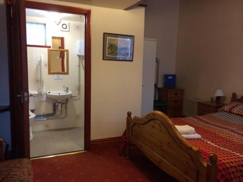 a bedroom with a bed and a bathroom with a sink at The Crown Hotel in Horton in Ribblesdale