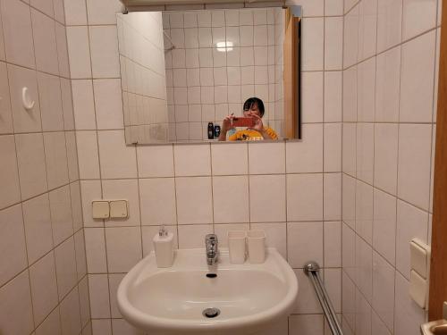une femme prenant une photo d'un lavabo dans la salle de bains dans l'établissement Mickten Hertz, à Dresde
