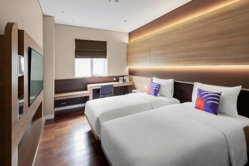 a hotel room with two beds and a television at FOX Lite Grogol Jakarta in Jakarta