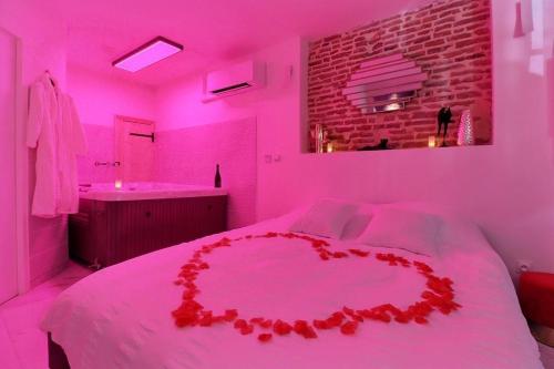 a pink room with a bed with a red heart on it at Love Room avec Jacuzzi Privatif Évasion Romantique à Castelsarrasin in Castelsarrasin