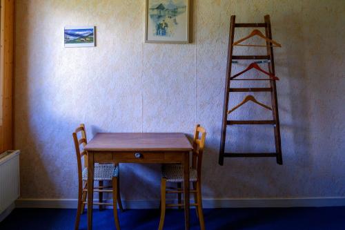 une table en bois avec deux chaises et une échelle dans l'établissement Les Roches Blanches, à Lanslebourg-Mont-Cenis
