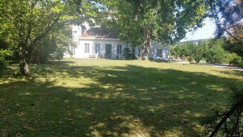 a white house with a large yard with trees at Chambres d'hôtes les Marronniers in Bordeaux