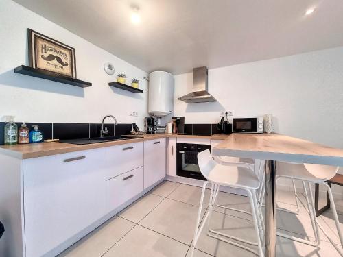 une cuisine avec des armoires blanches et une table avec des tabourets dans l'établissement Chez Lisa-Maison de ville à Concarneau, à Concarneau