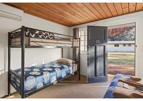a bedroom with two bunk beds and a door at Discovery Resorts - Glen Helen in Glen Helen
