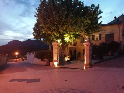 a tree in front of a building with lights at La maison d'Yvette - Gîte avec piscine, terrasse privée et vue in Le Barroux