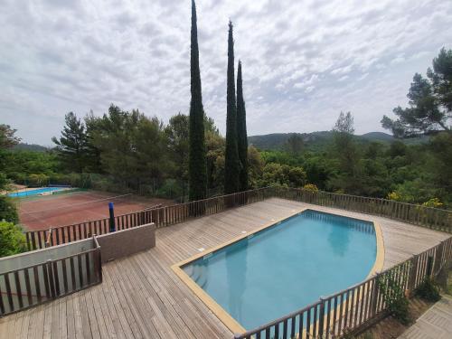 - une piscine sur une terrasse en bois à côté d'un court de tennis dans l'établissement T3 Le Lou-Piscine & Parking - 5min des thermes, à Gréoux-les-Bains