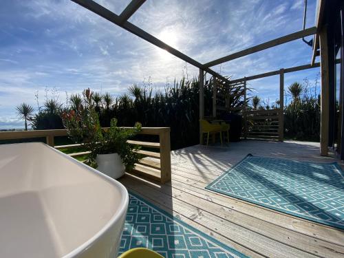 a deck with a bath tub and a view of the ocean at Ross Beach TOP10 Holiday Park in Ross