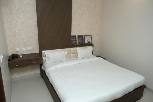 1 dormitorio con 1 cama grande con sábanas blancas en Hotel Singh Comfort Inn, en Gorakhpur