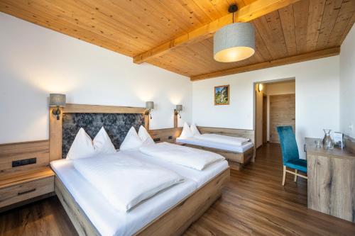 a bedroom with two beds and a blue chair at Berggasthof Höllenstein in Wagrain