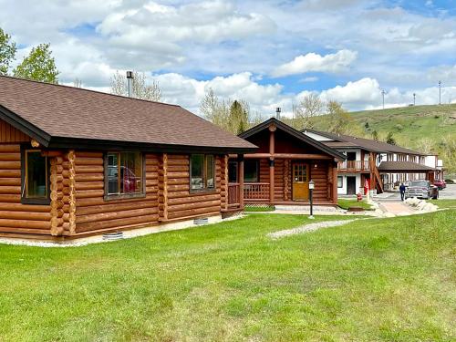 uma cabana de madeira com um relvado verde à sua frente em Beartooth Hideaway Inn & Cabins em Red Lodge