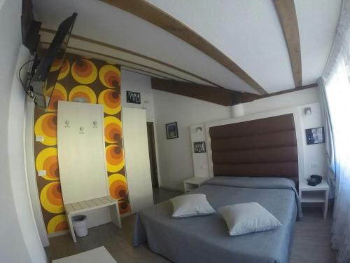 a bedroom with a bed and a wall with a painting at B&B Seventy Design in Dimaro
