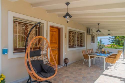 a porch with a table and a rattan chair at Fiorentinos Villa in Tragaki