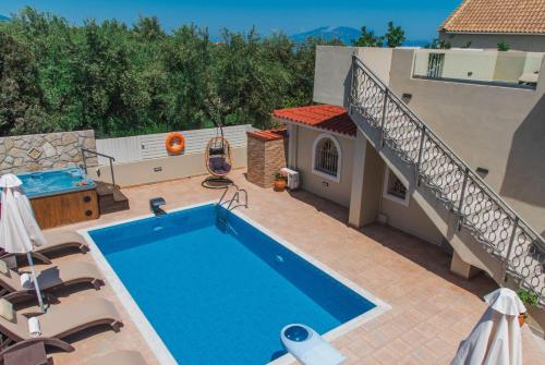 a swimming pool on a patio with chairs and a building at Fiorentinos Villa in Tragaki