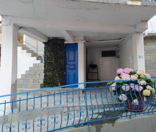 a balcony with a blue door and flowers in vases at Vasilis traditional House in Samothráki