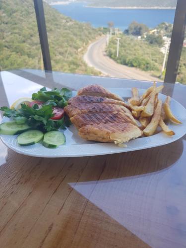 un piatto di cibo con bistecca e patatine fritte di Kaş Sun Glare Hotel a Kaş
