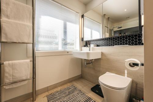 a bathroom with a toilet and a sink and a mirror at Moa Magic - Oneroa Holiday Home in Oneroa