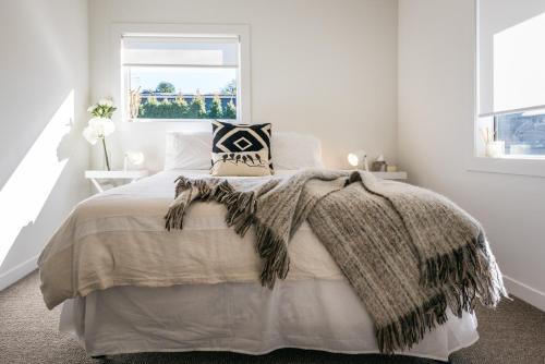 a bedroom with a bed with a blanket and a window at Moa Magic - Oneroa Holiday Home in Oneroa