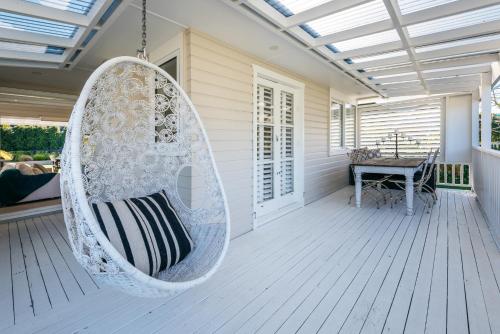 a swinging chair on a porch with a table at Moa Magic - Oneroa Holiday Home in Oneroa