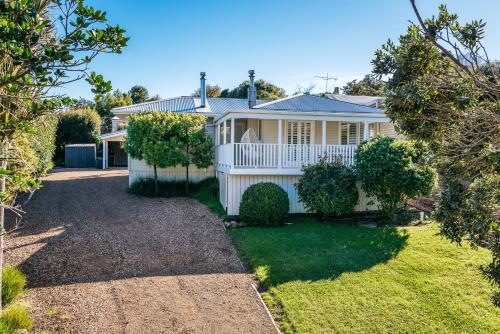 a white house with a porch and a yard at Moa Magic - Oneroa Holiday Home in Oneroa