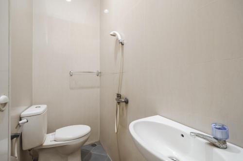 a white bathroom with a toilet and a sink at KoolKost near Hang Nadim Batam Airport (Minimum Stay. 30 Night) in Nongsa